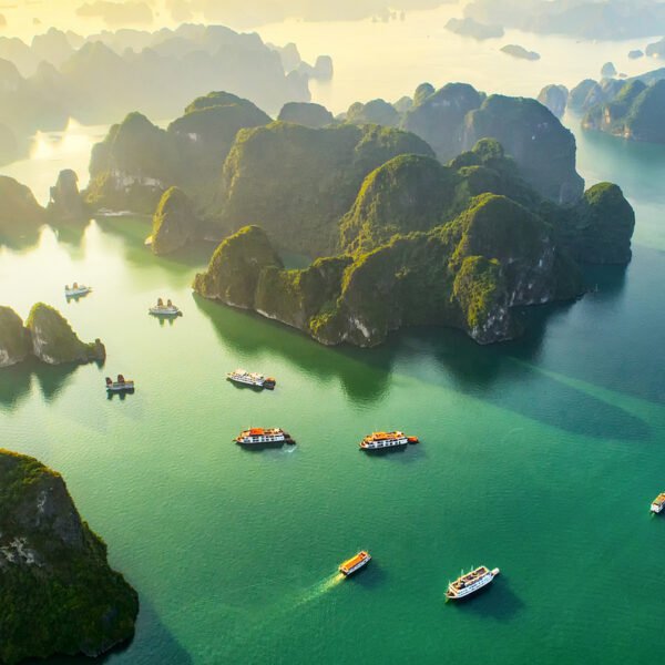 Vista aérea de ilhas calcárias e embarcações nas águas da baía de Ha Long, Vietnã.